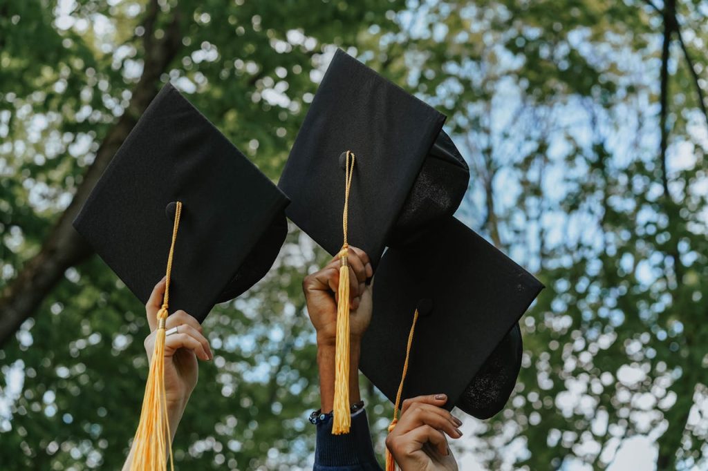 Three hands holding graduation caps in celebration, symbolizing success.