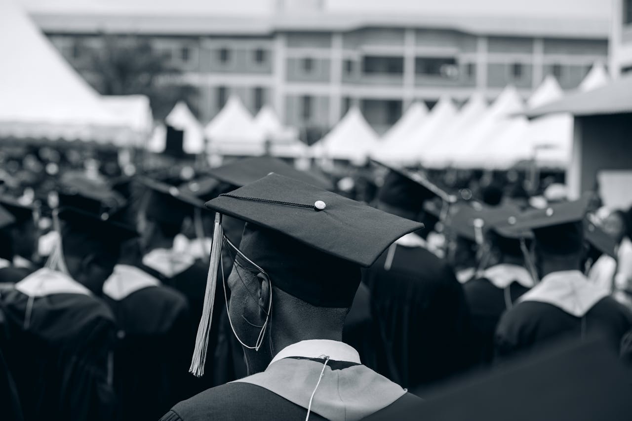 services-02 A black and white photo of students in caps and gowns at a university graduation ceremony outdoors.